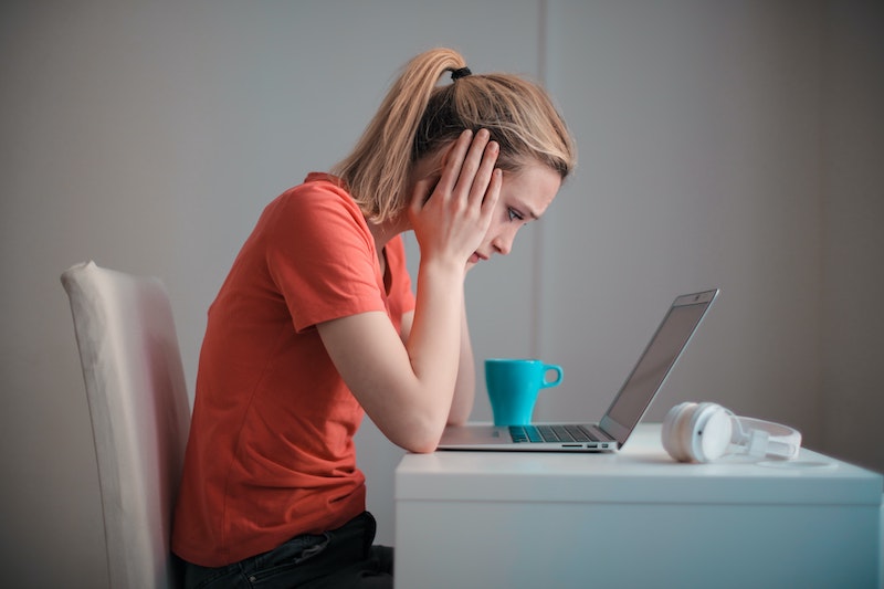 mulher em frente o computador com as mãos nos ouvidos