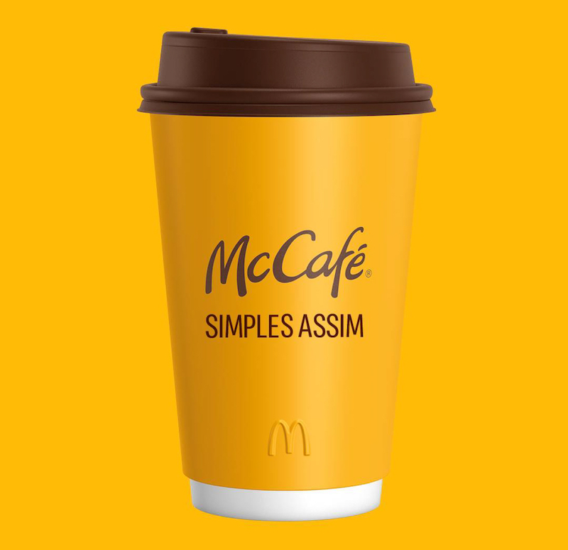 copo de café do mcdonalds amarelo com tampa marrom com a logo do MC CAFÉ e a frase SIMPLES ASSIM