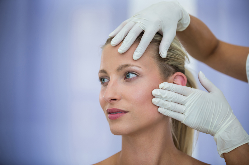 Médico examinando o rosto de pacientes do sexo feminino de tratamento cosmético