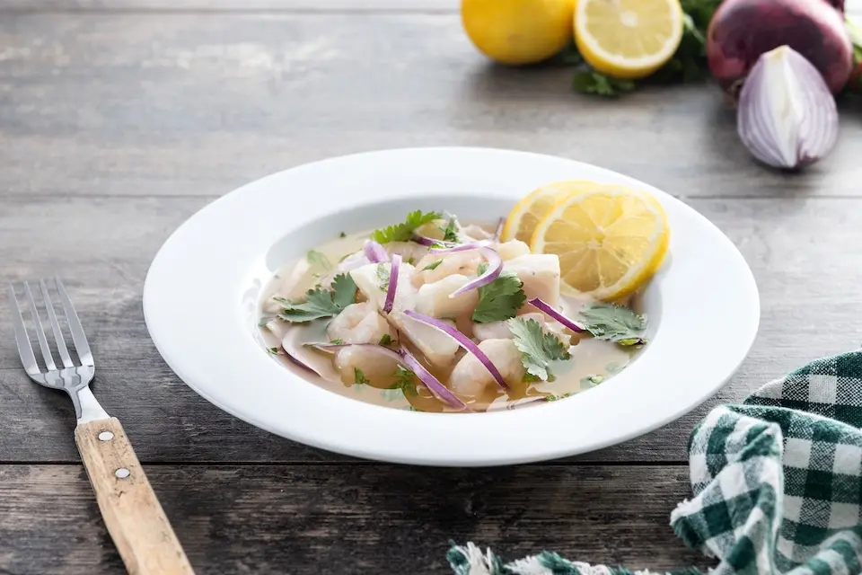 Filé de robalo ao ceviche tradicional peruano servido em mesa de madeira.