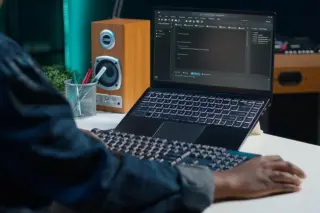 Profissional utilizando notebook com código de programação em ambiente de trabalho