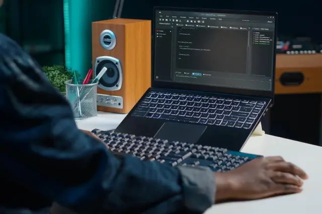 Profissional utilizando notebook com código de programação em ambiente de trabalho