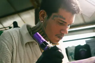 Tatuador Filipe Lima Leonório realizando uma tatuagem em seu estúdio