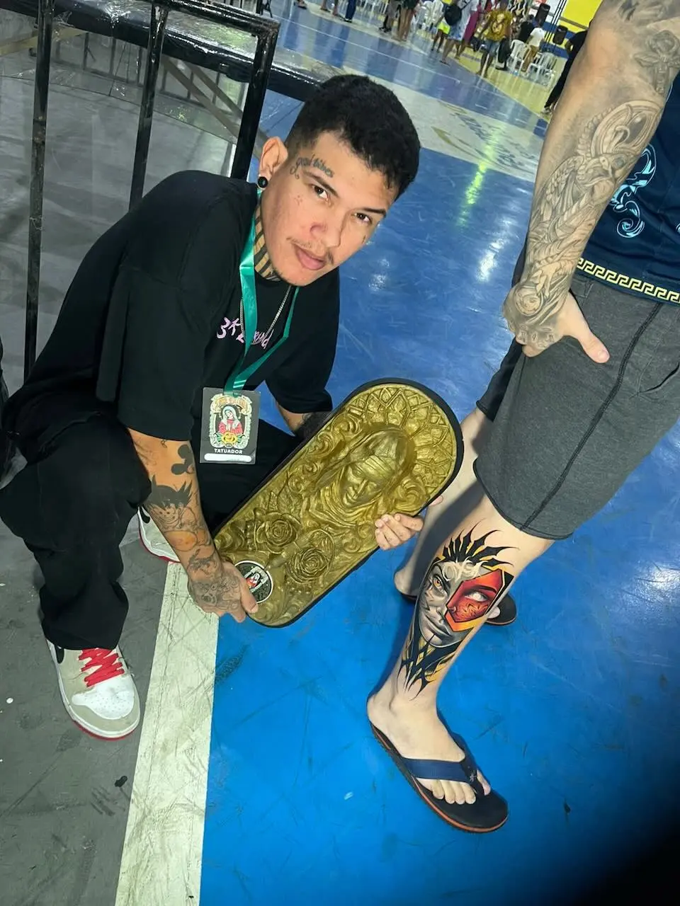 Filipe Lima Leonório com prêmio ao lado de trabalho apresentado em convenção de tatuagem
