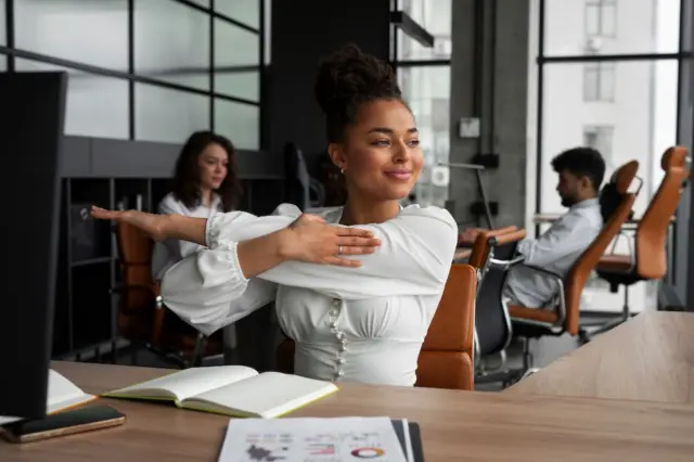 Mulher se alongando no ambiente de trabalho durante expediente