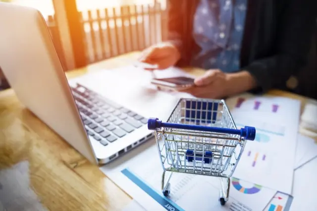 Mulher realiza compra online usando cartão e notebook
