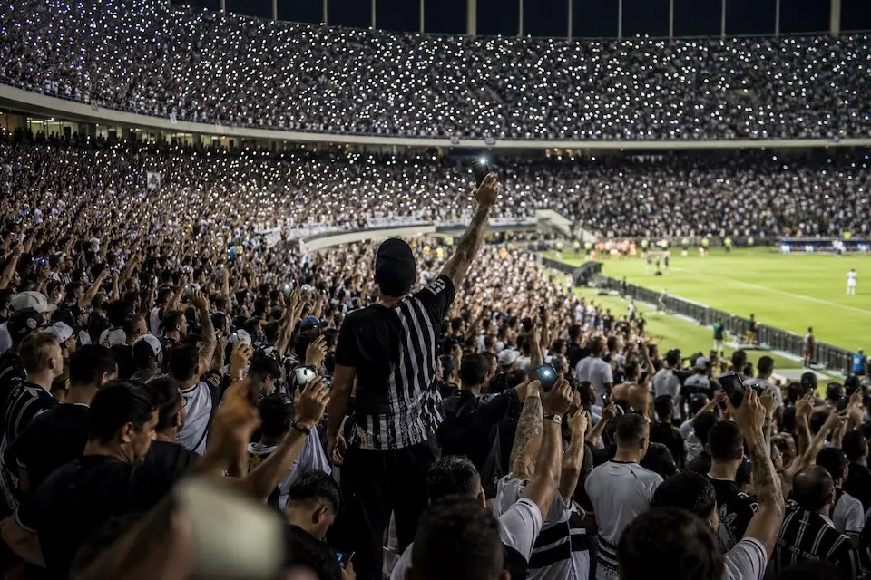 Torcida do Corinthians em estádio com celulares acesos durante manifestação de apoio a jogador