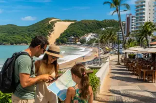 Família consulta mapa diante da Praia de Ponta Negra, em Natal, com o Morro do Careca ao fundo