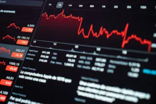 Tela com gráficos financeiros em queda ilustrando a redução da Taxa Selic