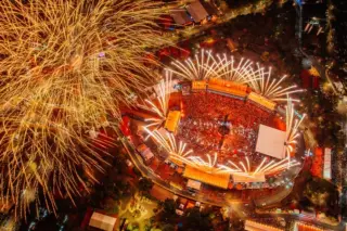 Vista aérea noturna do Parque do Peão com público no centro e fogos de artifício no céu