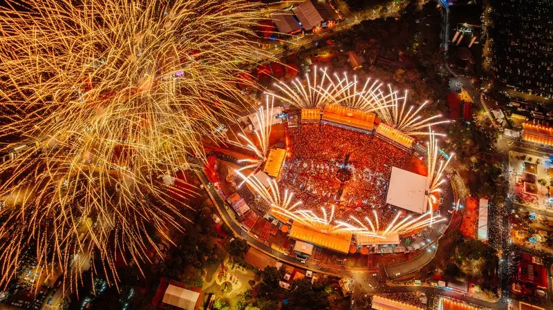 Vista aérea noturna do Parque do Peão com público no centro e fogos de artifício no céu