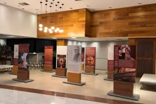 painéis expositivos verticais com textos e imagens dispostos em corredor de shopping, bancos e luminárias no teto