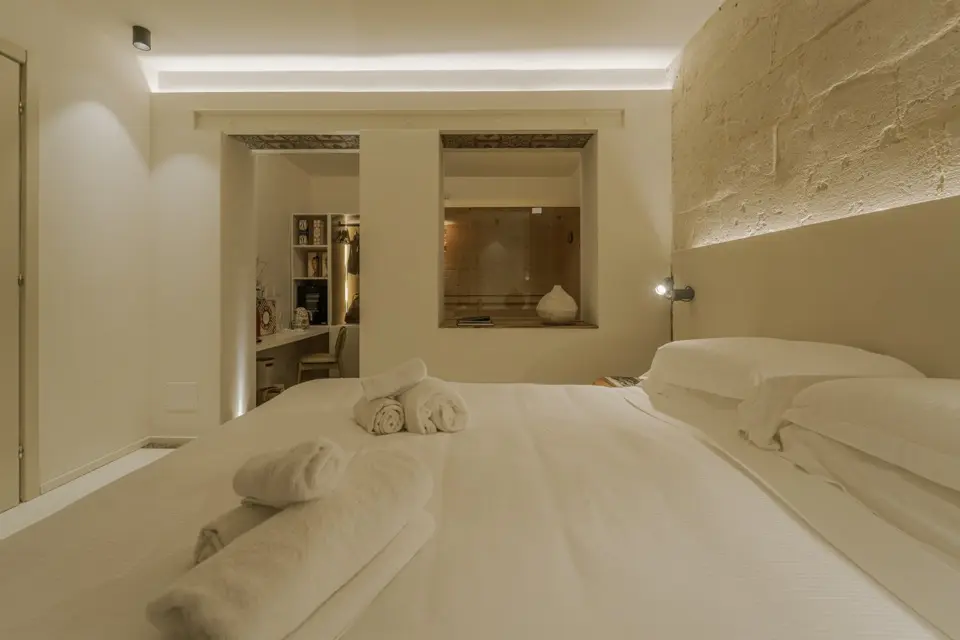 Quarto com duas camas de solteiro, decoração clara e varanda com cadeiras azuis
