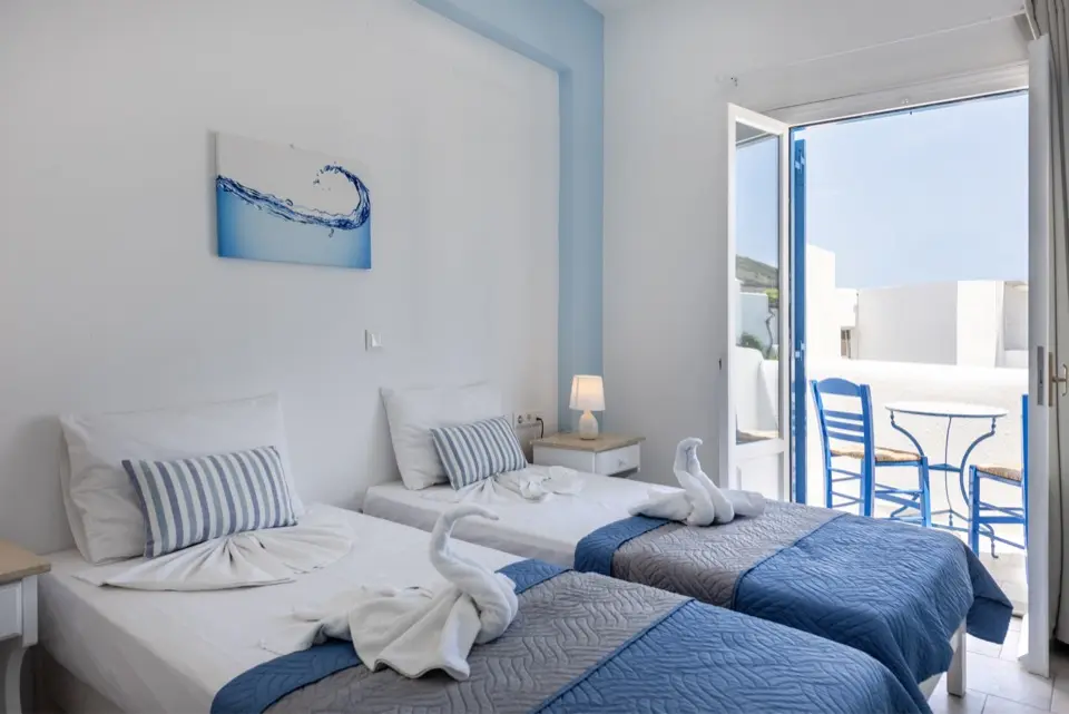 Quarto minimalista com cama de casal, iluminação indireta e toalhas dobradas sobre a cama