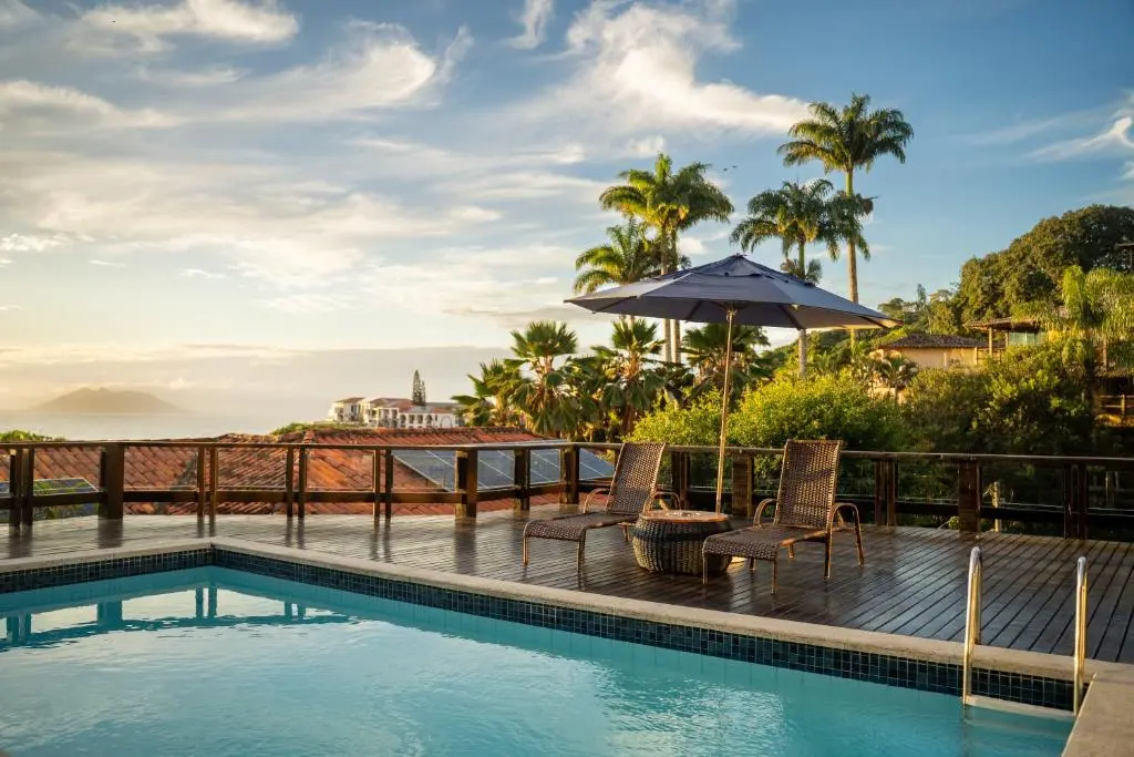 piscina com borda e espreguiçadeiras com vista para o mar azul e horizonte