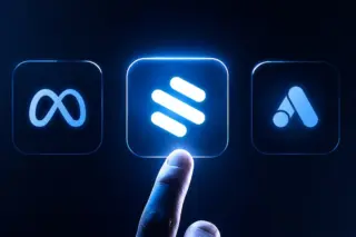 Dedo apontando para ícone central iluminado entre três ícones quadrados com símbolos de plataformas, sobre fundo azul escuro