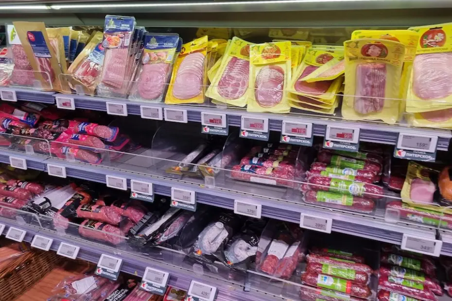 prateleira refrigerada com embalagens de embutidos e produtos cárneos processados fatiados e em pacotes, com etiquetas de preço visíveis