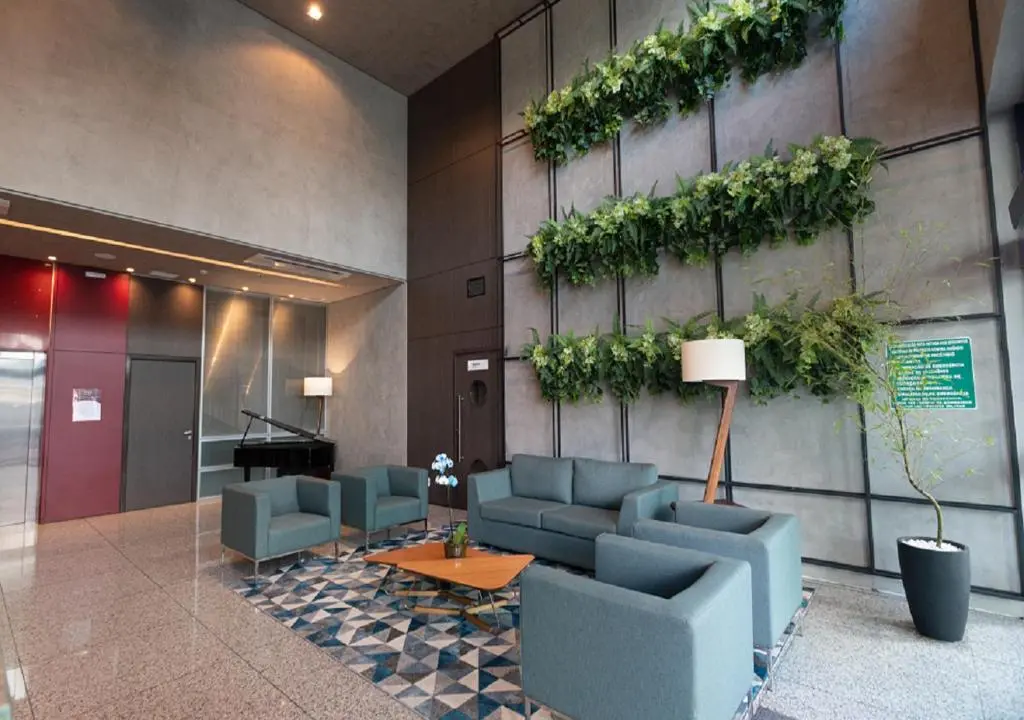 Lobby com sofá e poltronas azuis e parede com plantas verticais