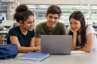 Estudantes reunidos em torno de notebook durante atividade de estudos e inscrição online