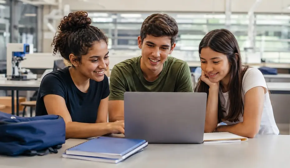 Estudantes reunidos em torno de notebook durante atividade de estudos e inscrição online