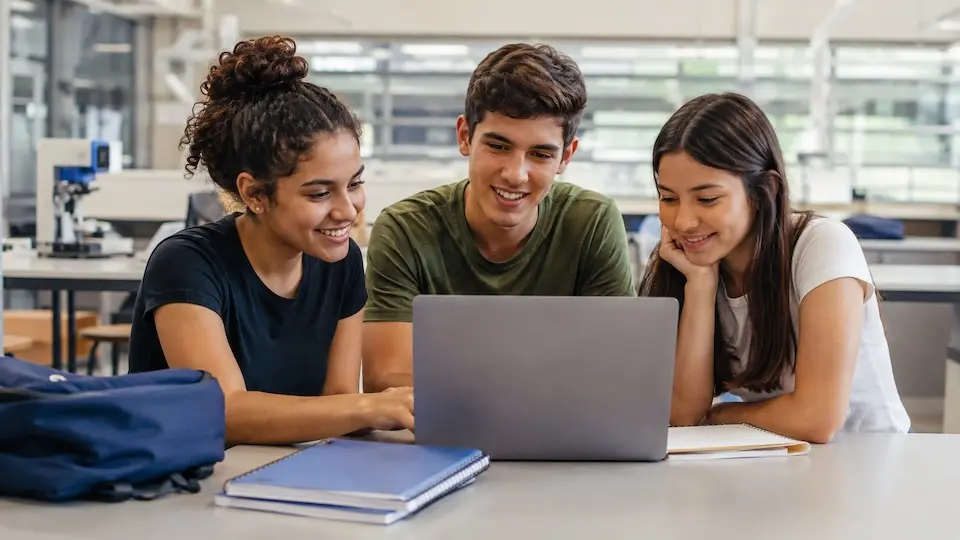 Estudantes reunidos em torno de notebook durante atividade de estudos e inscrição online