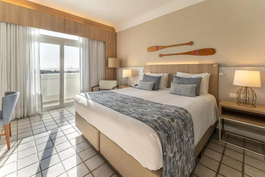 Quarto com cama, varanda de vidro e remos decorativos na parede