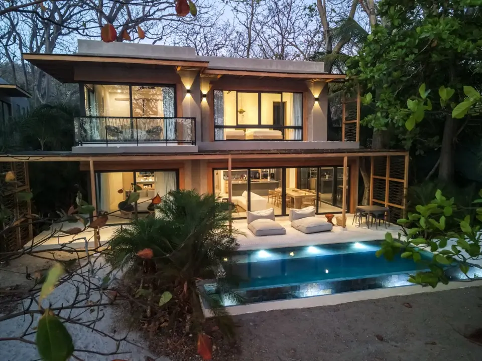 Fachada de acomodação com duas plantas, varanda envidraçada, área externa iluminada e pequena piscina estreita