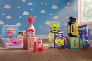 Conjunto de produtos infantis Sophie e Next inspirados em Toy Story dispostos sobre piso de madeira com parede azul decorada com nuvens