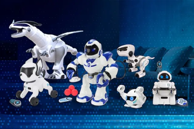 Vários brinquedos robóticos brancos e azuis dispostos sobre fundo azul, incluindo um robô humanoide, um dinossauro robótico, rovers, controles remotos e três bolinhas vermelhas