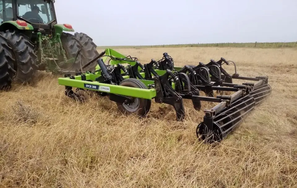 Trator acoplado a implemento agrícola verde com identificação 'EPCR 300' e logotipo Piccin, em área de pastagem seca