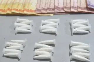 Microtubos plásticos brancos dispostos em grupos sobre superfície cinza e cédulas de dinheiro parcialmente visíveis no topo