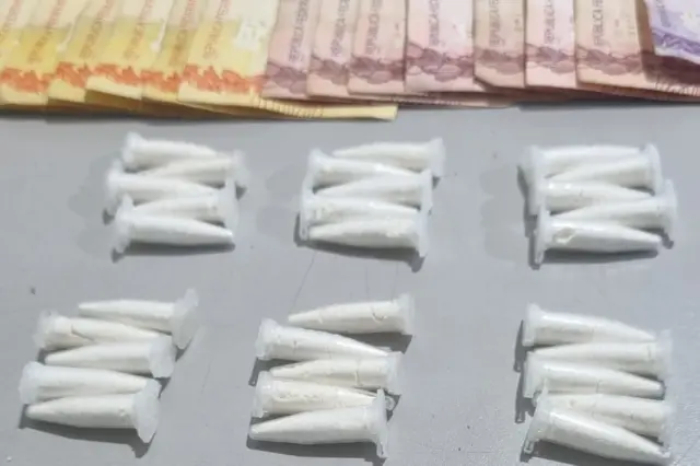Microtubos plásticos brancos dispostos em grupos sobre superfície cinza e cédulas de dinheiro parcialmente visíveis no topo