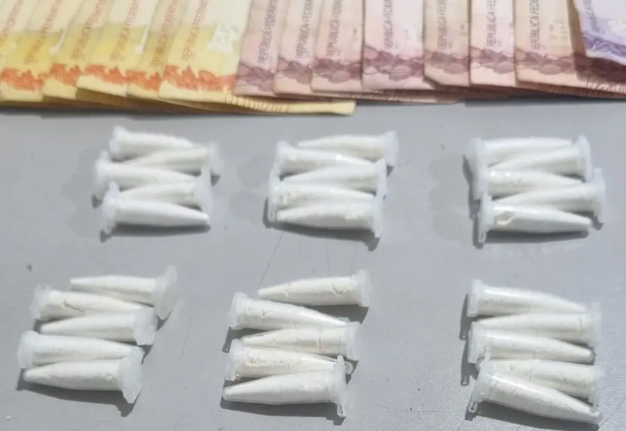 Microtubos plásticos brancos dispostos em grupos sobre superfície cinza e cédulas de dinheiro parcialmente visíveis no topo