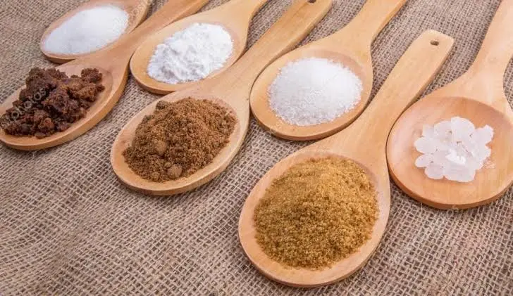 colheres de madeira com vários tipos de açúcar sobre tecido de juta