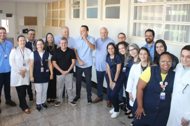 Profissionais de saúde e autoridades posando em corredor de hospital