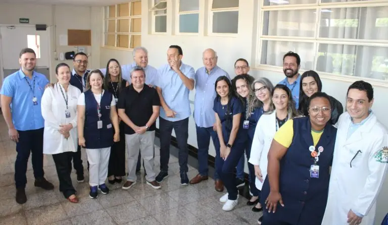 Profissionais de saúde e autoridades posando em corredor de hospital