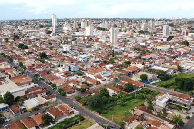 Vista aérea do centro urbano de Barretos com casas, ruas, áreas verdes e alguns prédios mais altos ao fundo