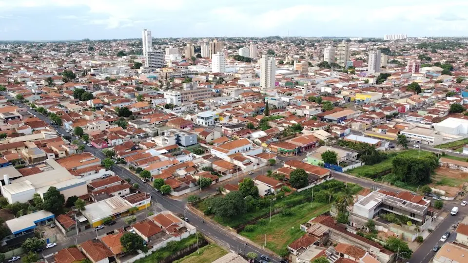 Vista aérea do centro urbano de Barretos com casas, ruas, áreas verdes e alguns prédios mais altos ao fundo
