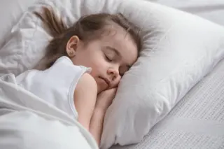 menina dormindo de lado sobre travesseiro branco