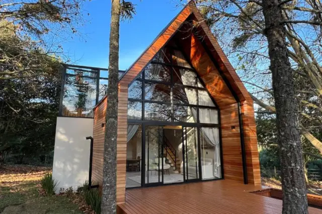 quarto com cama de casal, colcha listrada em tons de azul e verde e banheiro visível