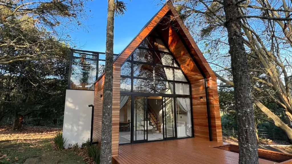 quarto com cama de casal, colcha listrada em tons de azul e verde e banheiro visível