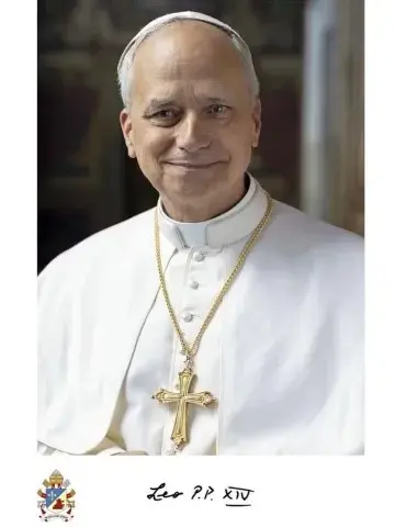 Homem idoso com batina branca e crucifixo dourado ao peito, sorrindo levemente, fundo interno desfocado