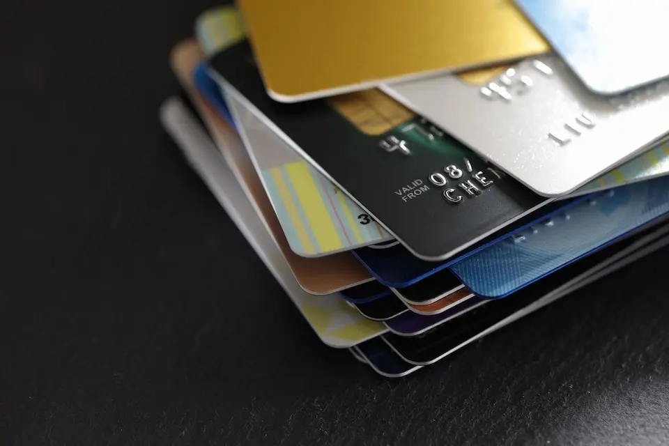 pilha de cartões de crédito e débito coloridos sobre superfície escura