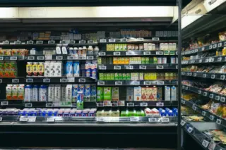 prateleiras refrigeradas de supermercado com embalagens de leite, bebidas e produtos lácteos e etiquetas de preço