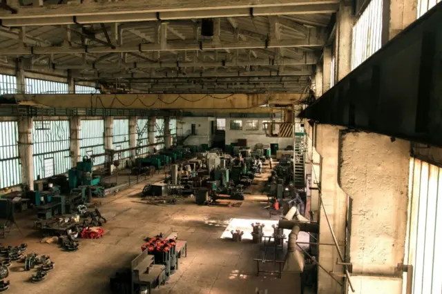 interior de um galpão industrial com máquinas e equipamentos distribuídos pelo piso