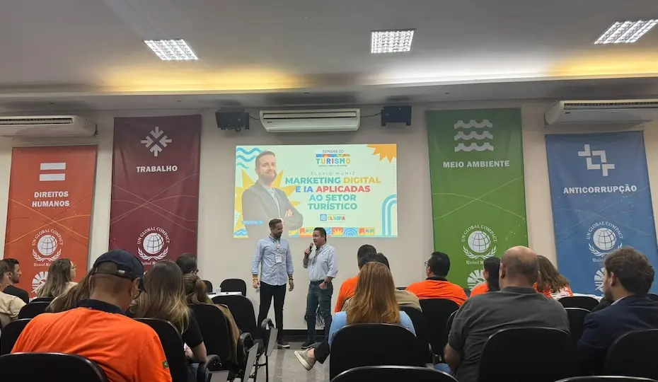 Plateia sentada de costas observa dois palestrantes no palco com telão sobre marketing digital e IA e faixas verticais temáticas nas laterais