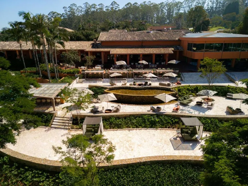 sala com sofá branco, poltronas com peles, carpete e portas de vidro com vista para deque e área verde