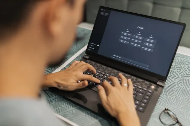 Pessoa digitando em notebook com a interface do ChatGPT visível na tela