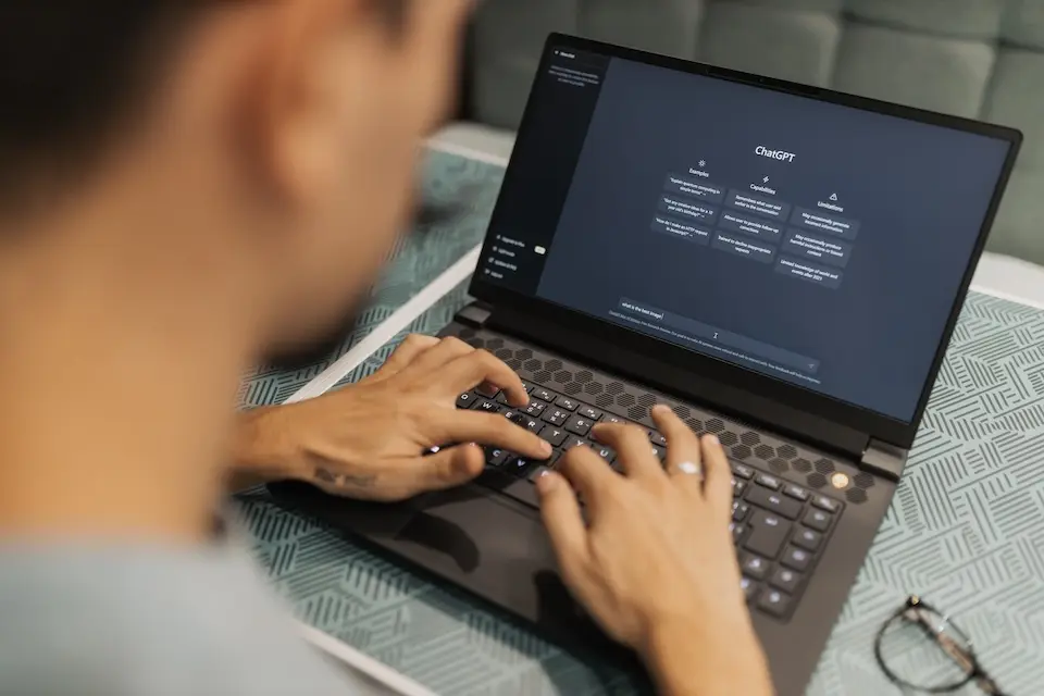 Pessoa digitando em notebook com a interface do ChatGPT visível na tela