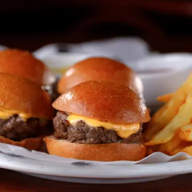 hambúrguer alto com crispy onion, folhas verdes e camadas de queijo e bacon